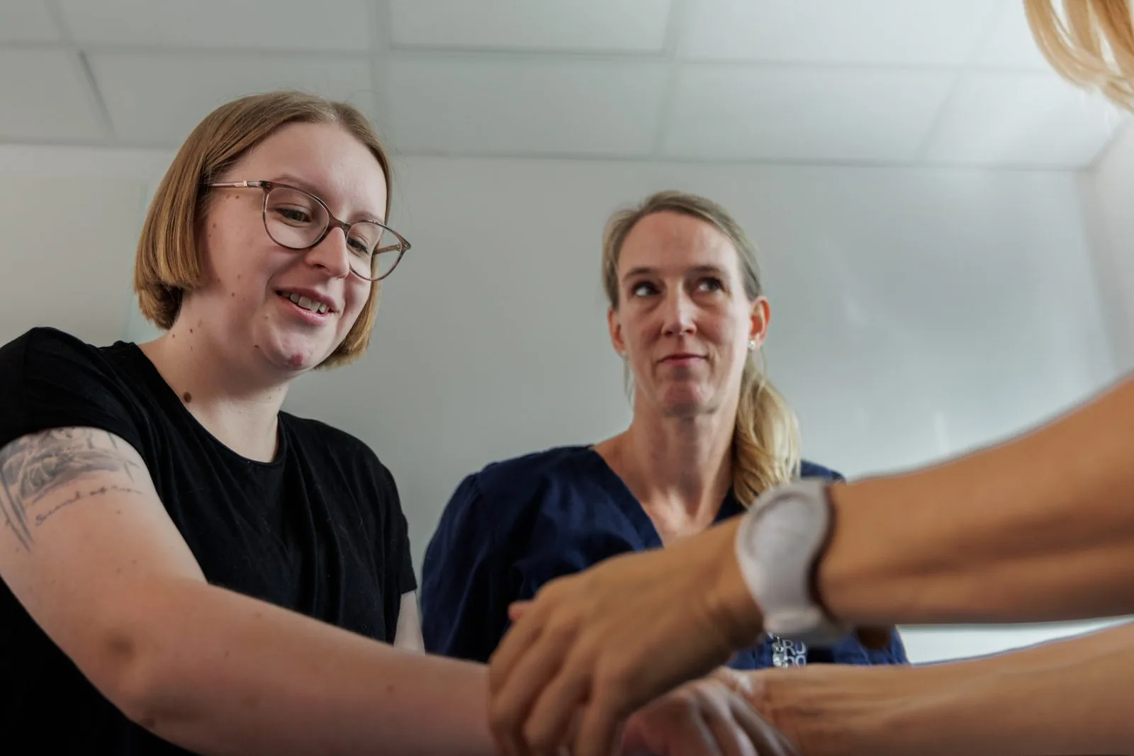Zwei Therapeutinnen der Praxis ErgoLogo arbeiten gemeinsam an einer Hand