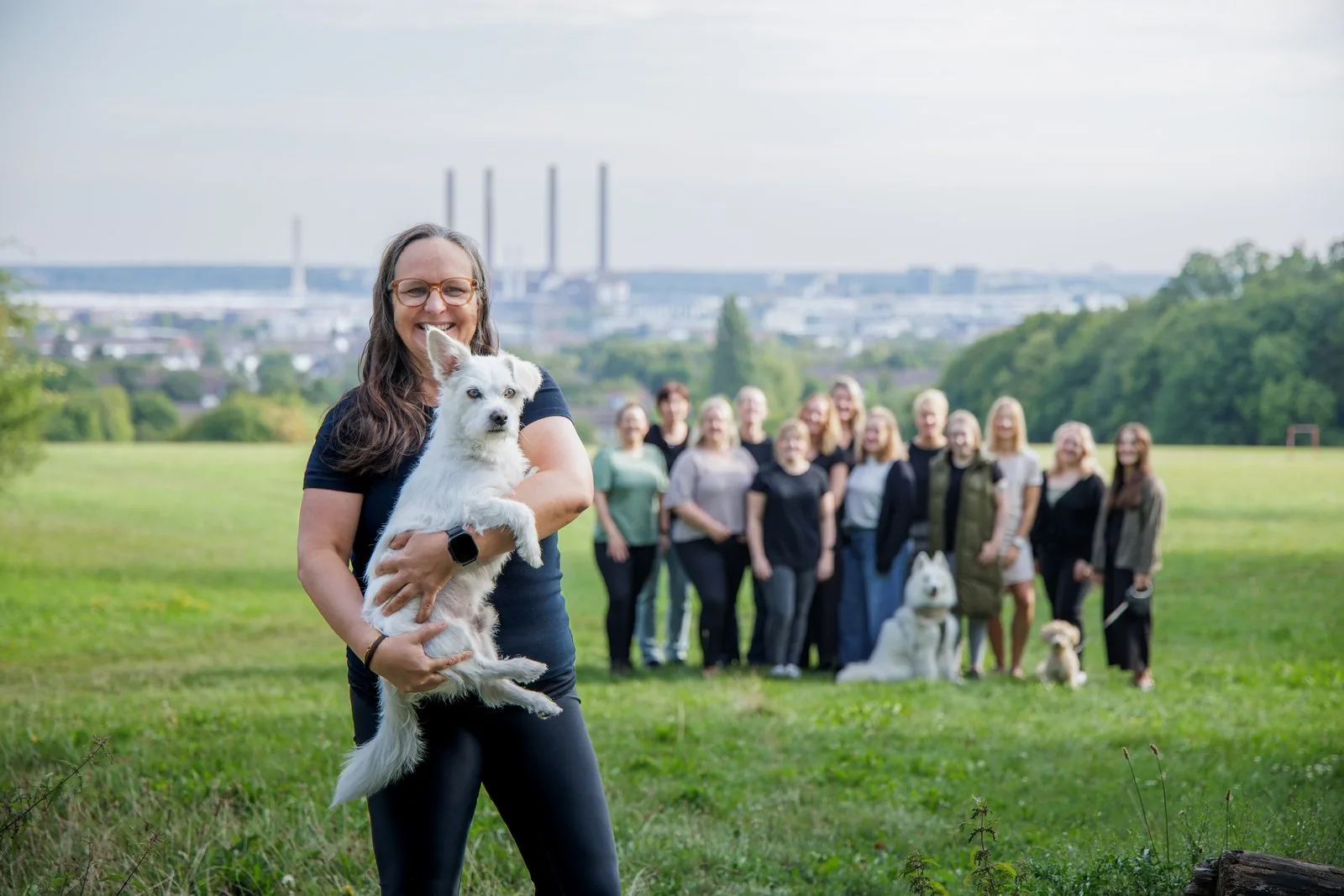 Celine Olschewski, Gründerin und Inhaberin der Praxis ErgoLogo, mit Therapiebegleithund Bruno auf dem Arm – dahinter das Team